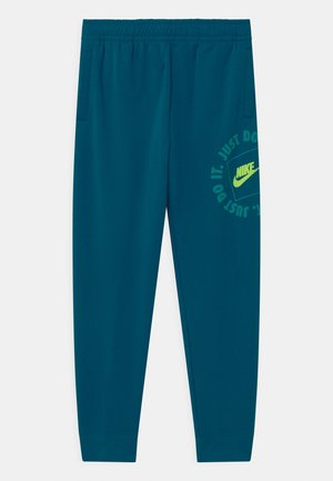 Turkusowe spodnie dresowe Nike z elastycznym pasem, kieszeniami po bokach i żółtym logo Nike z napisem "Just Do It" na prawej udzie.