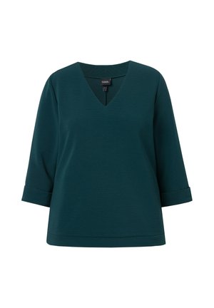 Turkusowy top w kształcie litery V z rękawami o długości trzech czwartych i podwiniętymi mankietami, charakteryzujący się gładką teksturą i luźnym krojem.