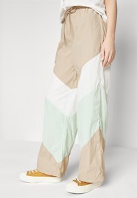 Lichte, kleurgeblokte broeken met een trekkoord in de taille; voorzien van beige, witte en mintgroene driehoekige patronen; relaxte pasvorm.