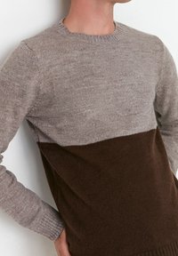 Maglione a girocollo con metà superiore grigio chiaro e metà inferiore marrone. Realizzato in morbido materiale lavorato a maglia con polsini a coste.