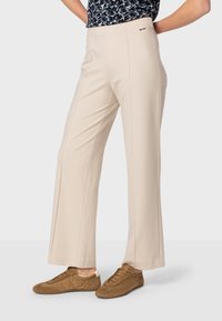 Beige wijde broek van zachte stof, met voornaad en een slank tailleband. Gekocht met bruine casual schoenen.