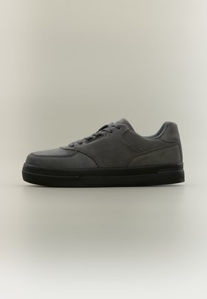 Baskets basses gris foncé avec semelle noire, fermeture à lacets à l'avant, en matière suédée, vues de profil sur fond neutre.
