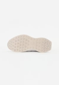 Suola della scarpa caratterizzata da una base in gomma flessibile e con texture, dotata di moduli esagonali rialzati per una migliore aderenza, di colore beige chiaro con dettagli marmorizzati.