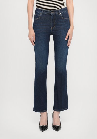 Ciemnoniebieskie jeansy dzwony z denimu o wąskim kroju w udach. Posiadają pięć kieszeni, szlufki na pasek oraz zapięcie na guzik. Nowoczesny design.