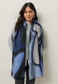 Long scarf featuring abstract patterns in shades of blue, gray, and black. Made of soft fabric with a light and flowing texture.