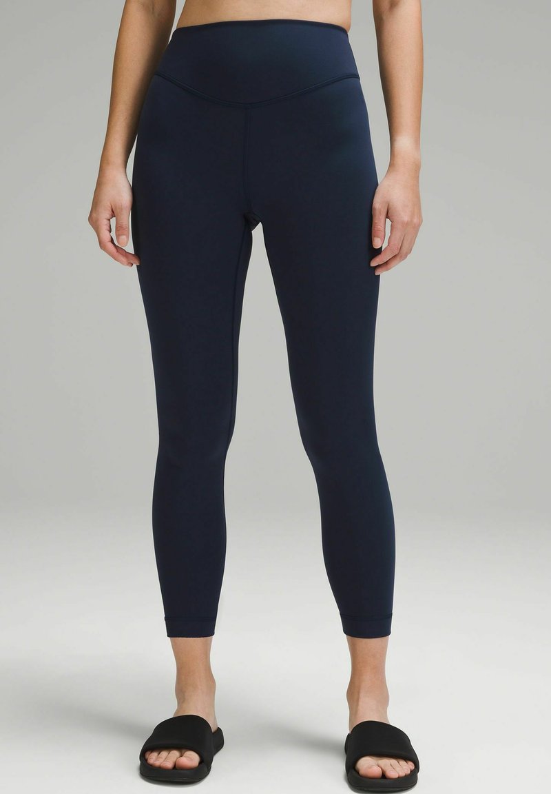 Hochgeschnittene Leggings in Marineblau aus glattem, dehnbarem Material mit einem taillierten Design und einer sauberen Verarbeitung. Keine sichtbaren Muster oder Beschläge.