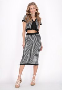 Crop top cu dungi alb-negru, cu mâneci scurte și fustă tip creion asortată. Textură țesută și model în zigzag. Espadrile de culoare deschisă.
