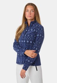 Granatowa kurtka polarowa z geometrycznym i śnieżynkowym wzorem w jasnym niebieskim. Posiada kołnierz, pełny zamek błyskawiczny oraz długie rękawy.