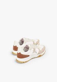 White and beige sneakers with suede accents, featuring a logo with a skull and crossbones, textured sole, and pink inner lining.