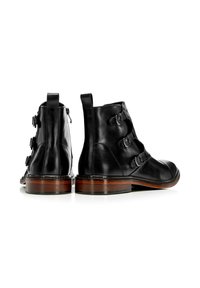 Botines negros de cuero con tres hebillas ajustables, textura suave, punta redonda y tacón de madera apilada. Cremallera lateral para mayor comodidad al ponerse.