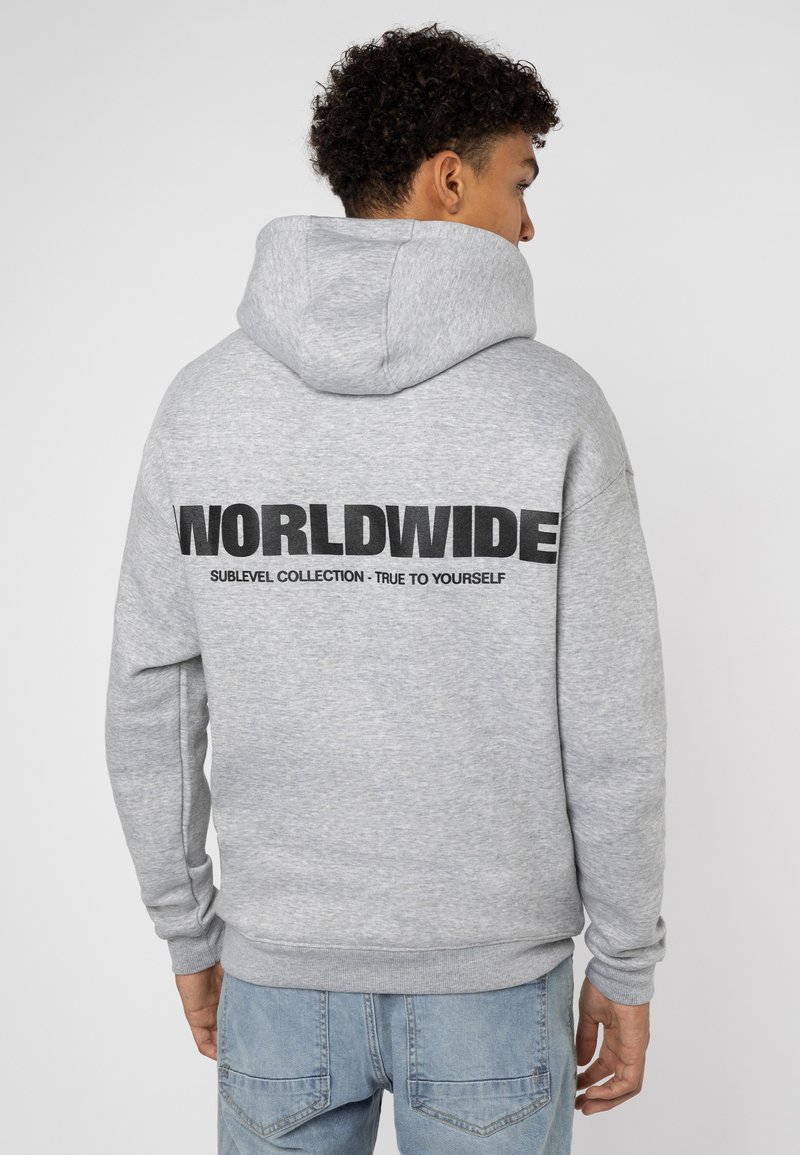 Grijze hoodie met een grote zwarte print op de achterkant met de tekst "WORLDWIDE" en kleinere tekst eronder. Bevat een buidelzak en ribgebreide manchetten.