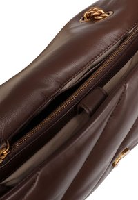 Bruine leren handtas met een gladde textuur, voorzien van een goudkleurige rits en kettingaccent. De binnenkant is gevoerd met een lichte stof.