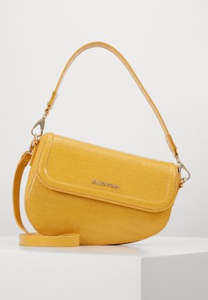 Žlutá kožená kabelka Valentino s krokodýlím vzorem, klopou na zavírání a odnímatelným popruhem, vystavená na bílém povrchu.