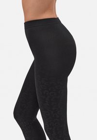 Leggings negros con un patrón de print de leopardo. Hechos de una tela elástica con una textura suave y una cinturilla elástica para mayor comodidad.