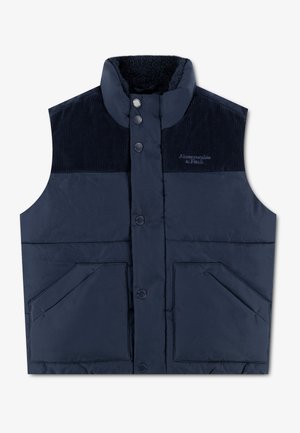 Veste matelassée sans manches bleu marine avec empiècements en velours côtelé aux épaules, boutons-pression, deux poches frontales et un col montant doublé en polaire.