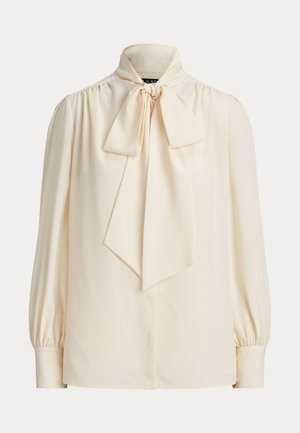 Langermet bluse i kremfarge med høy hals og stor knute i kragen, med oppsamlede puffskuldrer og mansjetter med knapper.