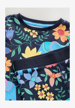 Tumesinine puuvillane komplekt, mis sisaldab elavaid lille- ja elevandimustreid sinises, kollases ja roosas, ning millel on ribatrepiga kaeluse ja varrukate äär.