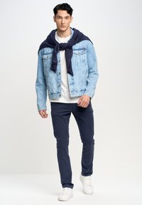 Jeans jakna v svetlo modri barvi, bela majica, mornarsko pulover, zavezan okoli ramen, mornarske hlače in bele superge. Preprost, sproščen videz.