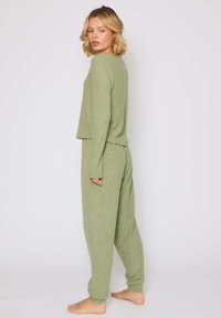 Grønt ribstrikket loungewear sæt bestående af en langærmet bluse med en afslappet pasform og matchende tætsiddende bukser. Blød tekstur, afslappet design.