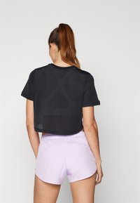 Melnā acs īsā krekliņš ar īsām piedurknēm, kombinēts ar gaiši lavandas šortiem. Krekliņš izceļas ar gaisa caurlaidīgu dizainu un teksturētu audumu.