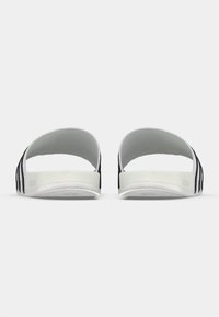 Μαύρα και λευκά σανδάλια slide με ανοιχτή φτέρνα, υφασμένο λευκό πέλμα και ριγέ σχέδιο στο πάνω μέρος. Κατασκευασμένα από συνθετικό υλικό.