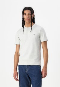 Lys grå kortærmet t-shirt lavet af blødt stof, med et lille logo på brystet og et klassisk crew neck design.
