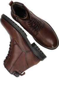 Bottines en cuir marron avec finition texturée, bout rond et design à lacets. La semelle en caoutchouc noir présente un motif de semelle robuste.