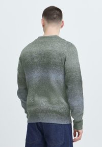 Grønn gradient genser med rund hals, ribbestrikkede mansjetter og kant. Laget av mykt strikket materiale, med en teksturert overflate.