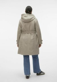 Abrigo de lana gris claro con capucha y cinturón, que presenta un corte entallado, mangas largas y un dobladillo trasero recto. Combinado con jeans acampanados y zapatillas.