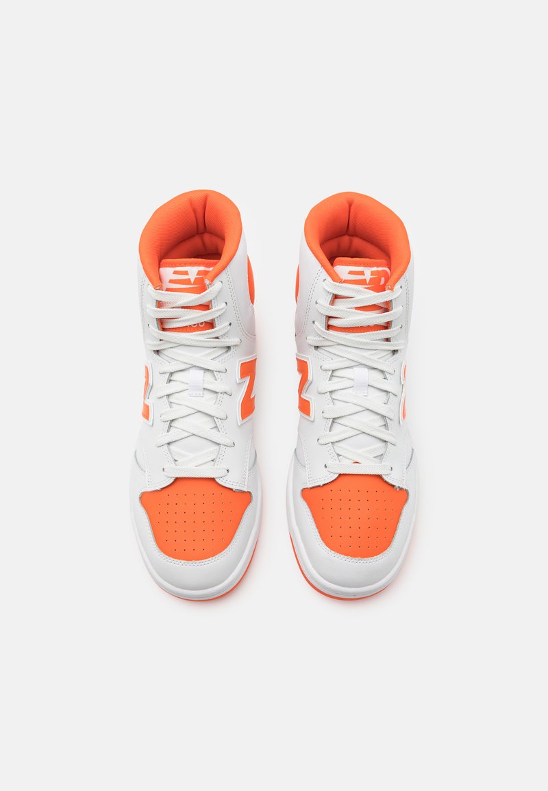 Zapatillas altas en blanco y naranja brillante. Material de cuero sintético, caja de dedos perforada, collar acolchado y acentos de logotipo en contraste.