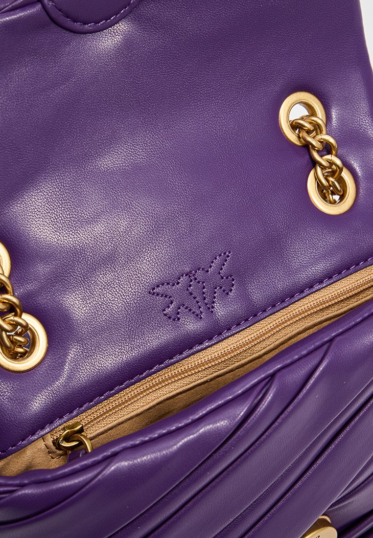 Borsa a tracolla in pelle viola con hardware dorato, caratterizzata da una superficie texturizzata, tasca con zip e un logo impresso sulla parte anteriore.
