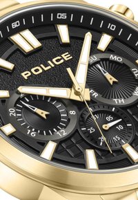 Orologio in tonalità oro con quadrante nero testurizzato, indici delle ore audaci, tre sottocronografi e una combinazione di finiture lucide e opache. Nome del marchio: POLICE.