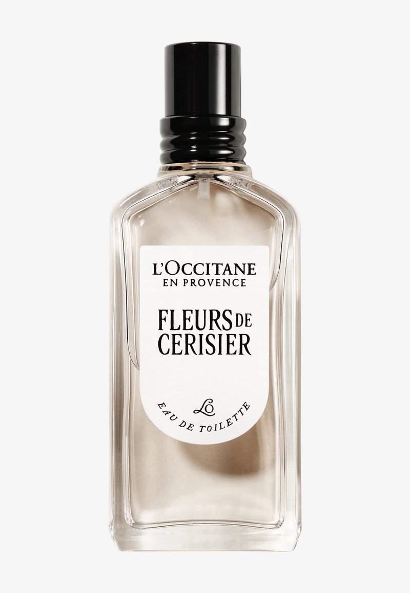 Transparent glaskanna med svart lock. Har en vit etikett med svart text. Innehåller en ljusfärgad vätska som representerar doften av körsbärsblommor.