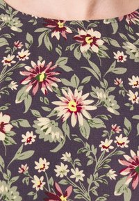 Tissu en coton à motif floral sur fond gris foncé, présentant de grandes fleurs roses et crème avec des feuilles vertes. Motif tricoté texturé.