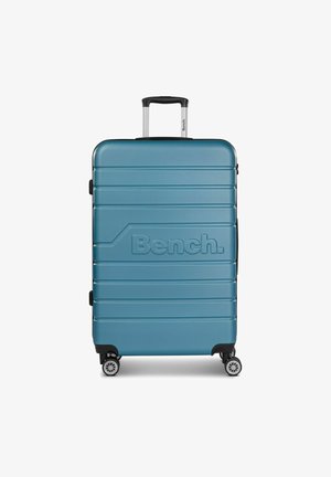 Valise rigide en teal avec un design rainuré, arborant un logo proéminent, une poignée télescopique et quatre roues pivotantes pour une meilleure mobilité.