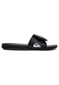 Black slide sandal with a textured footbed, soft upper strap, and white logo detail. Features a flat sole and minimalist design.