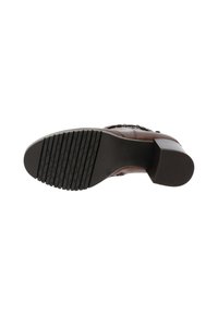 Chaussure à talon marron avec une semelle en caoutchouc texturé comportant des rainures horizontales et verticales. Tige en cuir avec des accents décoratifs et des coutures.