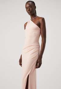 Rožinė, vieno peties suknelė iš tamprios medžiagos, turi raukšlėjimą šone ir aukštą įpjovą, sukurianti elegantišką siluetą.