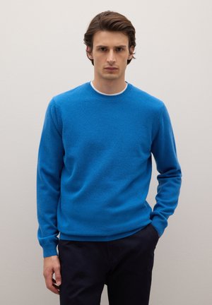 Blauer Pullover aus weichem Material mit Rundhalsausschnitt, langen Ärmeln sowie gerippten Bündchen und Saum. Trägt man über dunkler Hose.