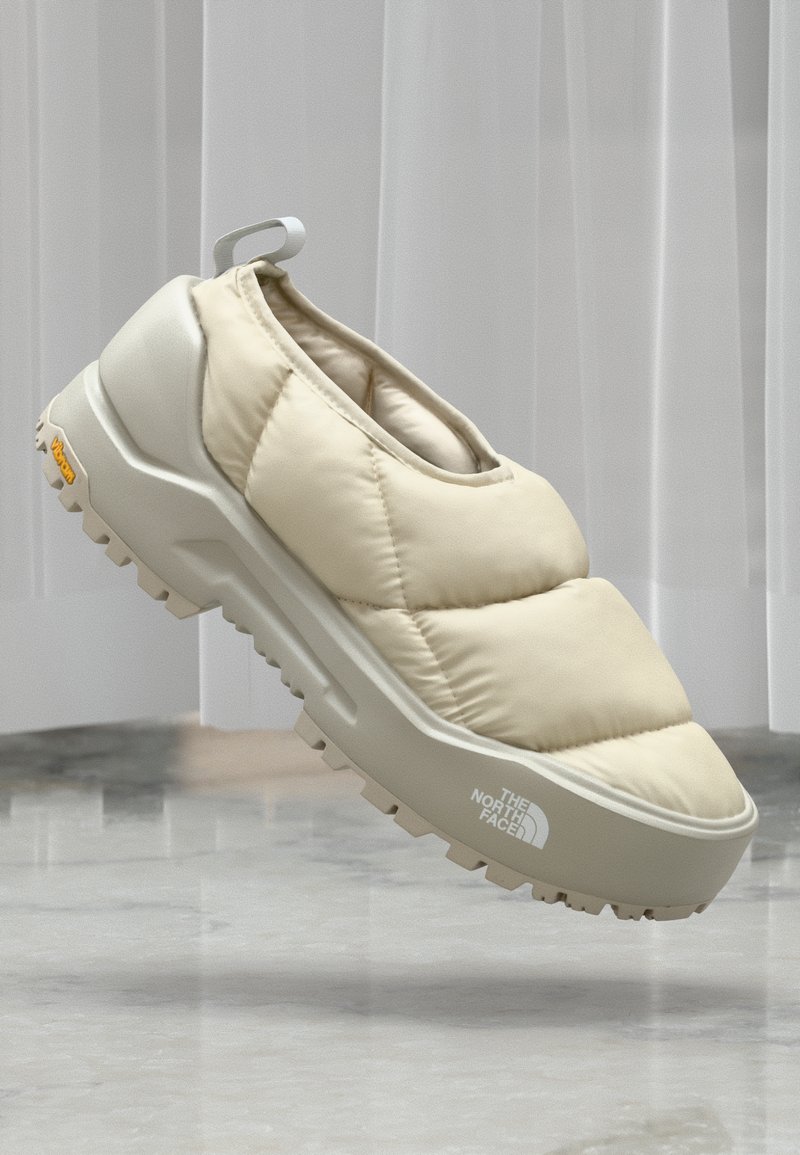 Chaussure à enfiler rembourrée beige avec une tige texturée, une semelle intermédiaire blanche épaisse et une semelle extérieure en caoutchouc robuste. Dispose d'une languette arrière et d'un détail de logo.