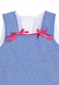 Blå denimkjole med hvidt stoffor, der har røde satinvendebånd, som er bundet i sløjfer på skulderstropperne.