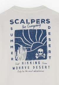 Bílá tričko s modrou grafikou, která obsahuje prvky pouště, lebku a texty jako "SCALPERS", "SUMMER" a "MOJAVE DESERT."
