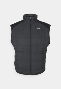 Gilet en duvet noir avec un col haut, une fermeture zippée à l'avant et des poches latérales. Présente un logo Nike sur la poitrine gauche et une texture matelassée.