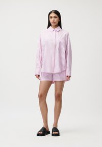 Langermet rosa stripete skjorte og matchende shorts i lett materiale, med en lomme og avslappet passform. Båret med svarte slip-on sandaler.