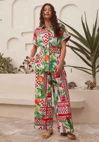 Színes két részes öltözék, rövid ujjú blúzzal és bő szárú nadrággal. Élénk zöld, piros és fehér virágos és geometrikus minták.