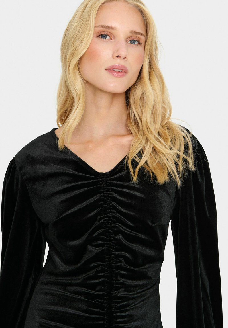 Schwarzes Samtkleid mit V-Ausschnitt, geraffter Textur entlang der Vorderseite und langen Puffärmeln. Glatte, weiche Oberfläche mit strukturierten Details.