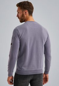 Fioletowy długi rękaw sweatshirt z okrągłym dekoltem, ściągaczami na rękawach i kieszenią naszytą na lewym rękawie, z teksturowanej tkaniny.