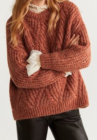 Pull en tricot couleur rouille avec motif texturé, doté d'un large col et de manches superposées avec des poignets en dentelle blanche. Conception en tissu doux et épais.