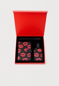 Set di astuccio in pelle nera e etichetta per bagagli con stampa di labbra rosse, presentato in una scatola rossa con interno nero e hardware dorato.