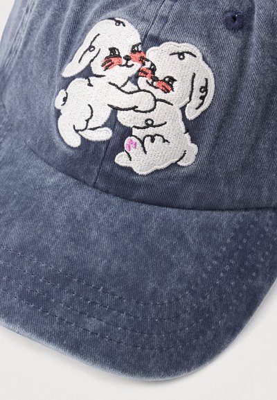 Blå kordflodshatt med broderad design av två vita kaniner med röda accenter. Har en böjd skärm och textilstruktur.